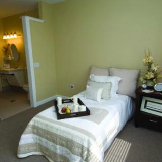 A cozy bedroom with a neatly made bed and a nightstand, featuring soft lighting and stylish decor.