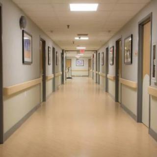 A sterile, empty hospital hallway with closed doors and fluorescent lighting.