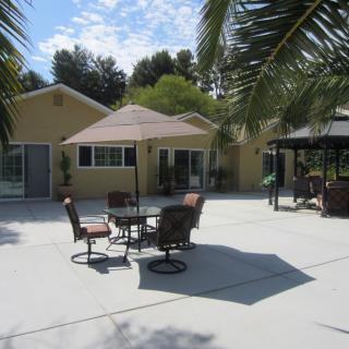 A sunny backyard patio with outdoor furniture and an umbrella.