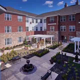 A well-maintained residential apartment complex with a central courtyard featuring a garden and outdoor seating areas.