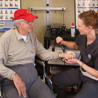 A healthcare professional assists an elderly patient during a medical check-up in a clinic.
