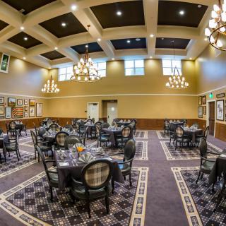 A spacious dining area with elegant chandeliers and neatly arranged tables and chairs.