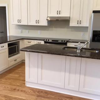 A modern kitchen featuring white cabinets, granite countertops, and stainless steel appliances with a central island.