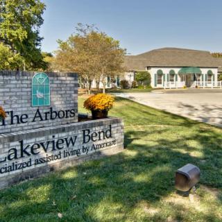 An outdoor view of The Arbors at Lakeview Bend entrance sign with a building in the background.