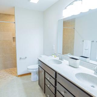 A modern bathroom with double sinks, a large mirror, and a glass-enclosed shower.