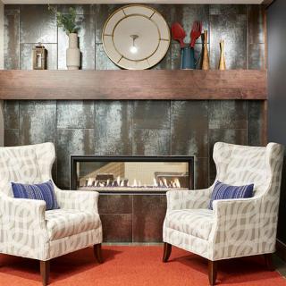 A modern living room setup featuring two patterned chairs, a central fireplace, and stylish decor.