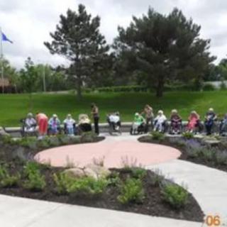 A group of people gathered in a park seating area surrounded by greenery.
