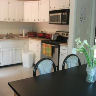 A modern kitchen with white cabinets and a dining area.