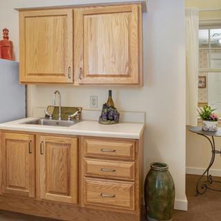 A cozy kitchen area featuring wooden cabinets and a small countertop with a sink, complemented by decorative items.