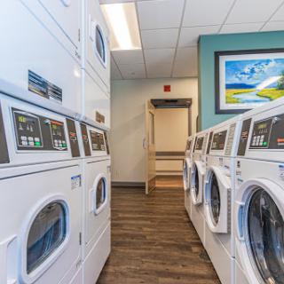 A modern laundry room equipped with efficient washing machines and dryers, featuring a comfortable and inviting atmosphere.