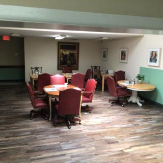 A cozy dining area with red upholstered chairs and wooden tables, complemented by artwork on the walls.