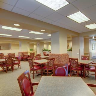 An empty dining area with several tables and chairs, well-lit by overhead lighting.