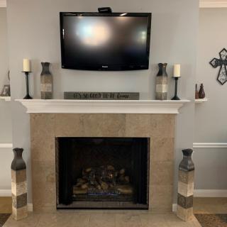 A modern living room with a fireplace and mounted TV, adorned with decorative vases, candles, and wall art.