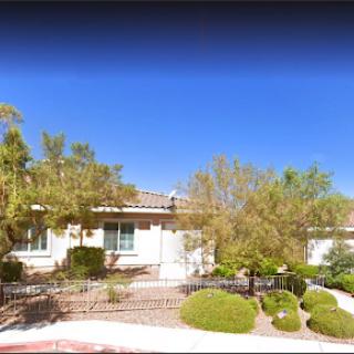 A charming residential house with landscaped greenery under a clear blue sky.