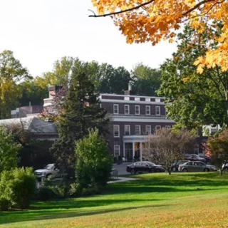A large building surrounded by trees and grass, showcasing the colors of autumn.