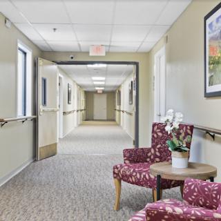 A serene hospital hallway featuring a comfortable waiting area with floral-patterned chairs.