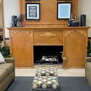 A cozy living room featuring a wooden fireplace with decorative elements and comfortable seating.