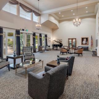 A spacious living room with elegant decor, featuring a piano and large windows.