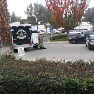 A food truck parked in a busy lot surrounded by autumn foliage.