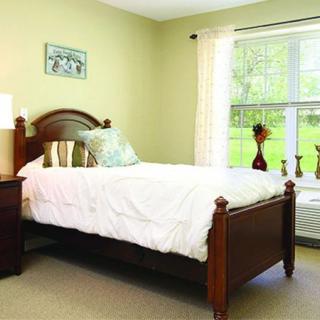A cozy bedroom with a wooden bed and a large window.