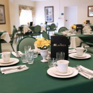 A neatly set dining table with green tablecloths and elegant place settings in a restaurant.