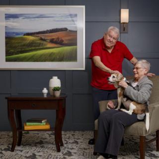 An elderly couple enjoying time together with their dog in a cozy living room.