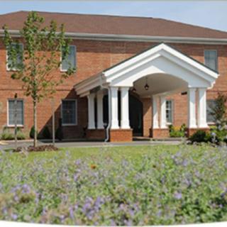 A brick building with white columns and landscaped surroundings.