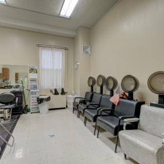 An empty beauty salon with multiple hair dryers and chairs.