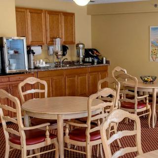 A cozy dining area featuring tables and chairs, with a coffee station in the background.