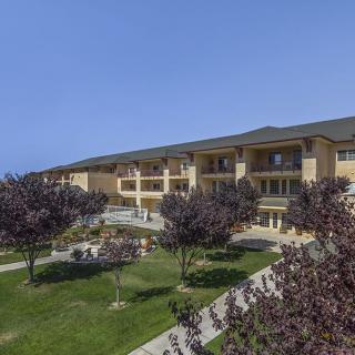 A spacious building surrounded by a well-maintained lawn and trees on a clear, sunny day.
