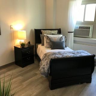 A cozy bedroom with a single bed, nightstand, and warm lighting.