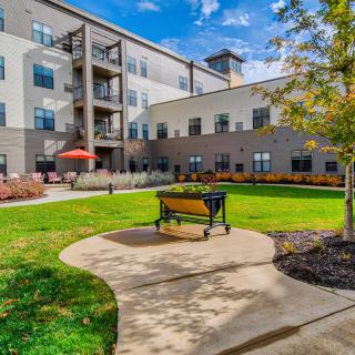 A courtyard view of a residential apartment building with a bench and landscaped garden.