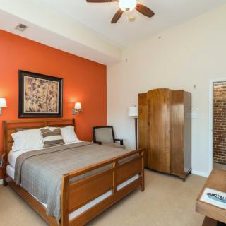 A cozy bedroom featuring a wooden bed, armoire, and an orange accent wall.