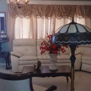 A traditional living room with elegant furnishings, including a sofa, floral arrangement, and a decorative lamp.