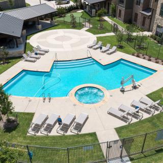 Aerial view of a residential swimming pool area with sun loungers and a hot tub.