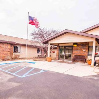 The entrance of a brick building with an American flag and designated handicap parking spaces.