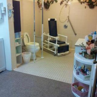 An accessible bathroom with safety equipment and a specialized chair.