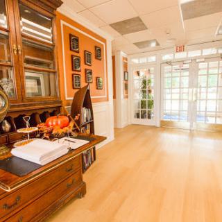An elegantly decorated office entryway featuring a wooden desk and display of awards.