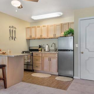A compact and modern kitchen interior with light wood cabinets, a small refrigerator, and a cozy dining area.