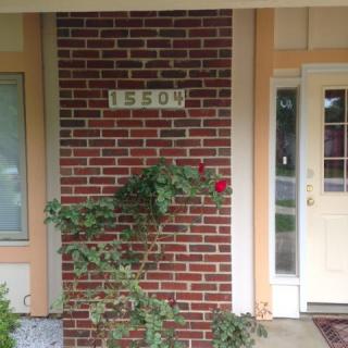 Front entrance of a house with a visible address and rose bush.