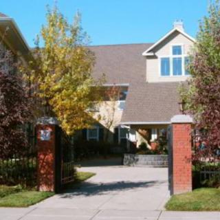 A suburban house with a driveway and gated entrance surrounded by trees.