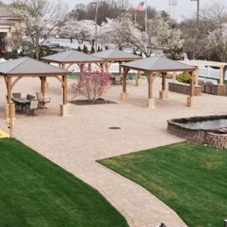A beautifully landscaped park with gazebos and a winding pathway, surrounded by springtime blossoms.