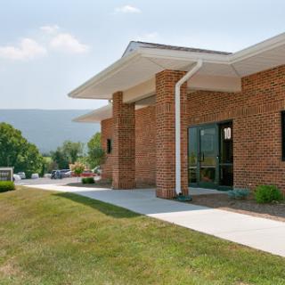 A modern brick building surrounded by green grass and a clear sky.