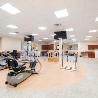 A well-equipped gym area featuring various exercise machines and a bright, spacious layout.