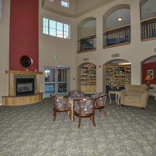 A spacious lobby with a cozy sitting area, bookshelves, and a fireplace.