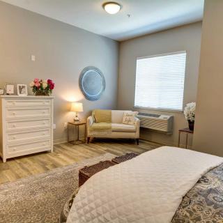 A cozy and modern bedroom with a comfortable armchair, dresser, and decorative elements.