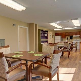 A spacious community dining and kitchen area with tables, chairs, and ample lighting.
