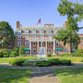 Historic hotel with American flag and lush green surroundings.