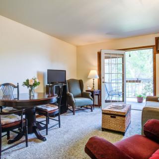 A cozy living room with comfortable seating, a TV, and access to a balcony.