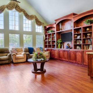 Spacious living room with large windows, wooden flooring, and built-in bookshelves.